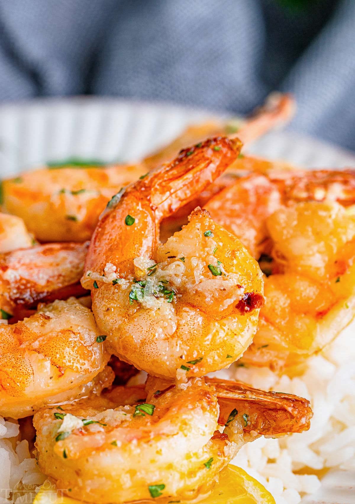 close up look at large shrimp cooked in air fryer topped with a garlic butter sauce sitting on a bed of white rice.