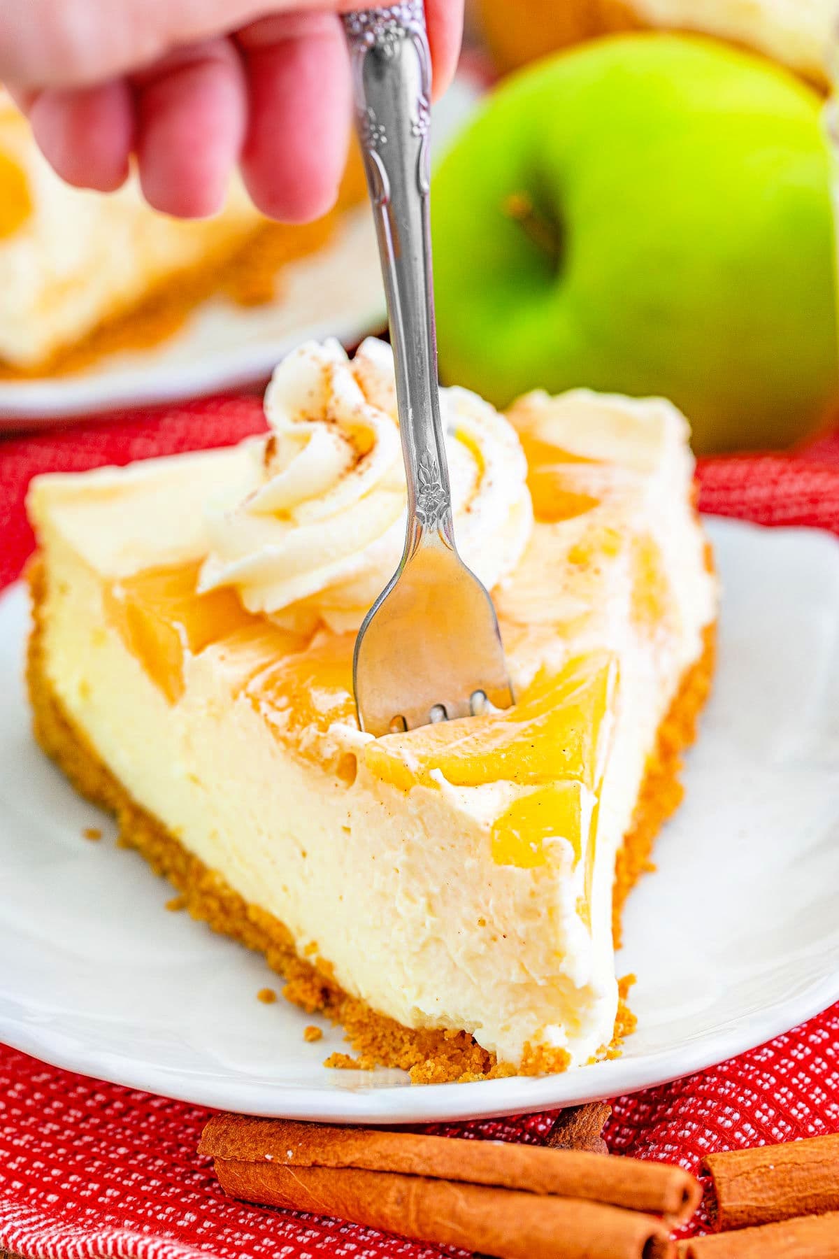 slice of no bake cheesecake with a fork stuck in it ready to take a bite.