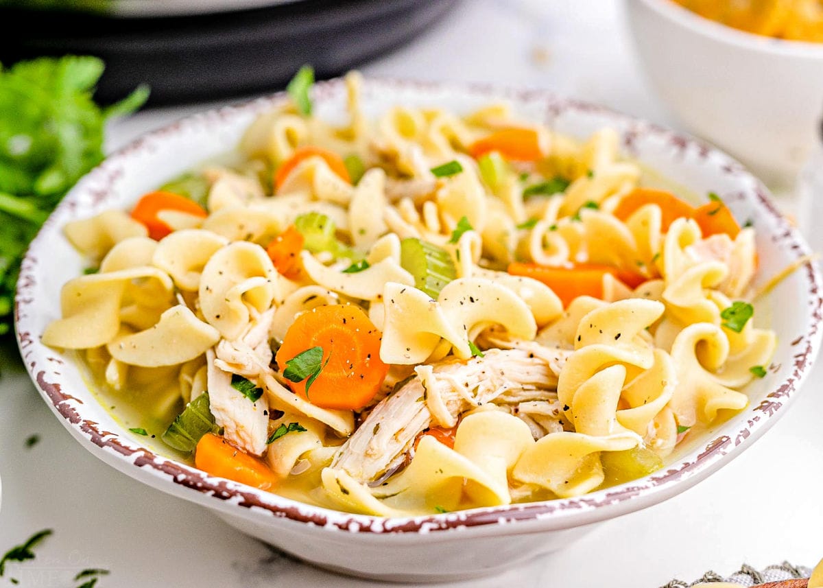 large white bowl filled with a generous serving of chicken noodle soup ready to be eaten.