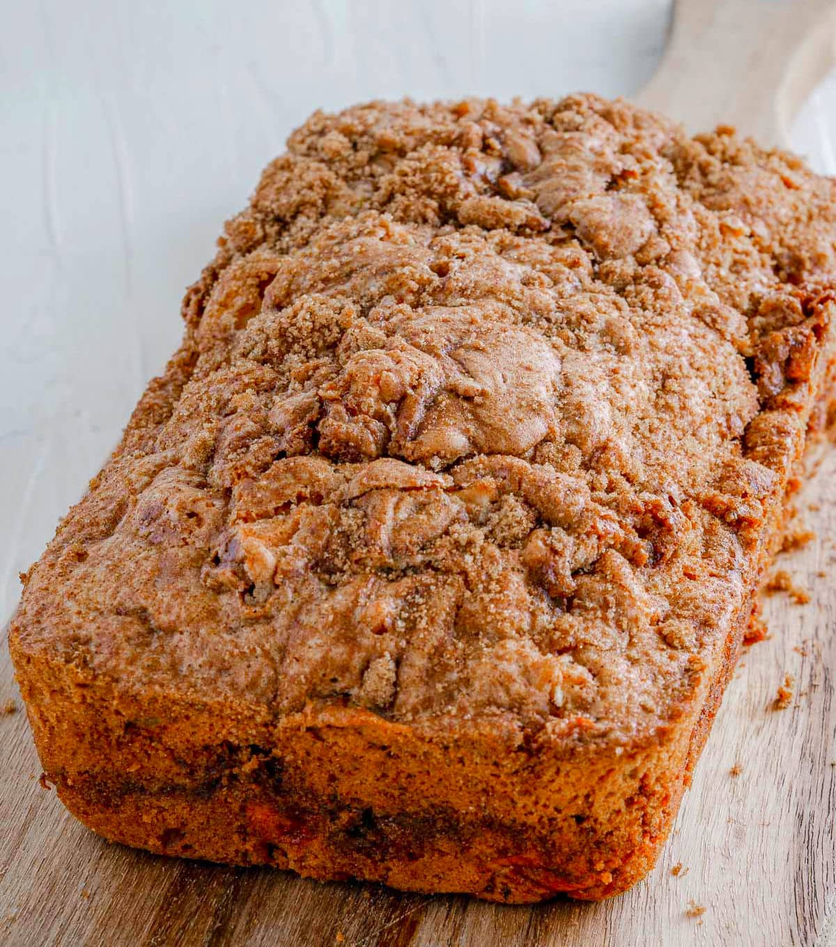 loaf of apple bread cooling on wood board.