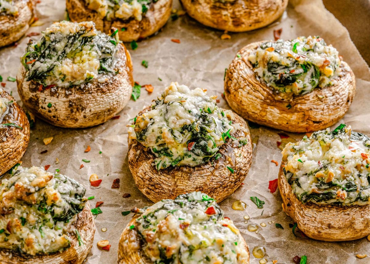 wide view of about 7 mushrooms stuffed with a creamy spinach filling and sprinkled with red pepper flakes and Parmesan cheese, ready to be enjoyed.