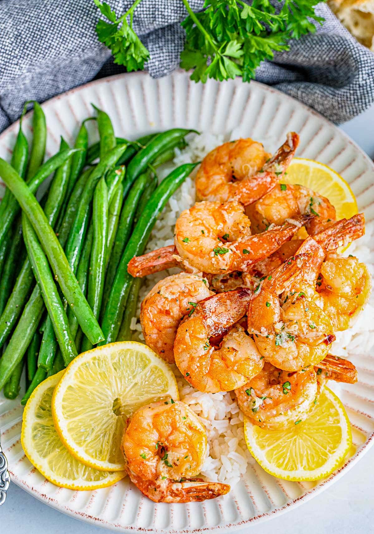 plate of air fryer shrimp topped with a garlic herb butter sauce.