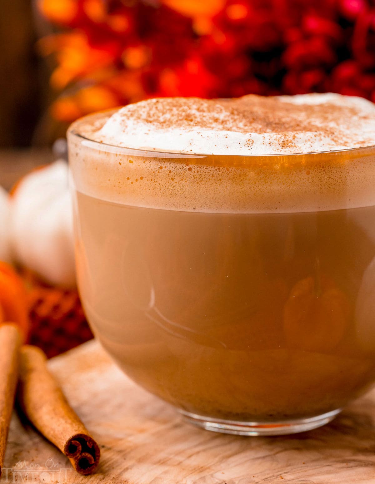 up close look at pumpkin spice latte made at home. Served in a glass mug and topped with frothed milk and pumpkin pie spice.