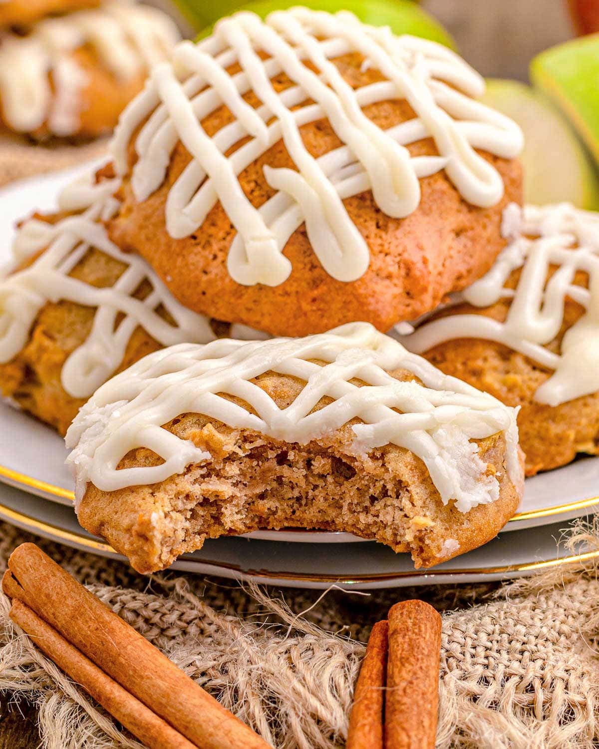 cookies made with apples on a small white plate with one cookie with a bite removed. icing is drizzle don top of all the cookies.