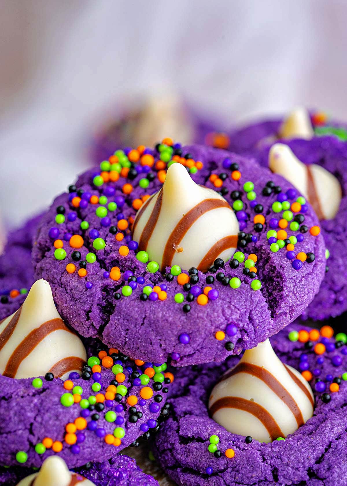 purple witch hat halloween cookies with sprinkles and hershey kisses pressed into the cookies.