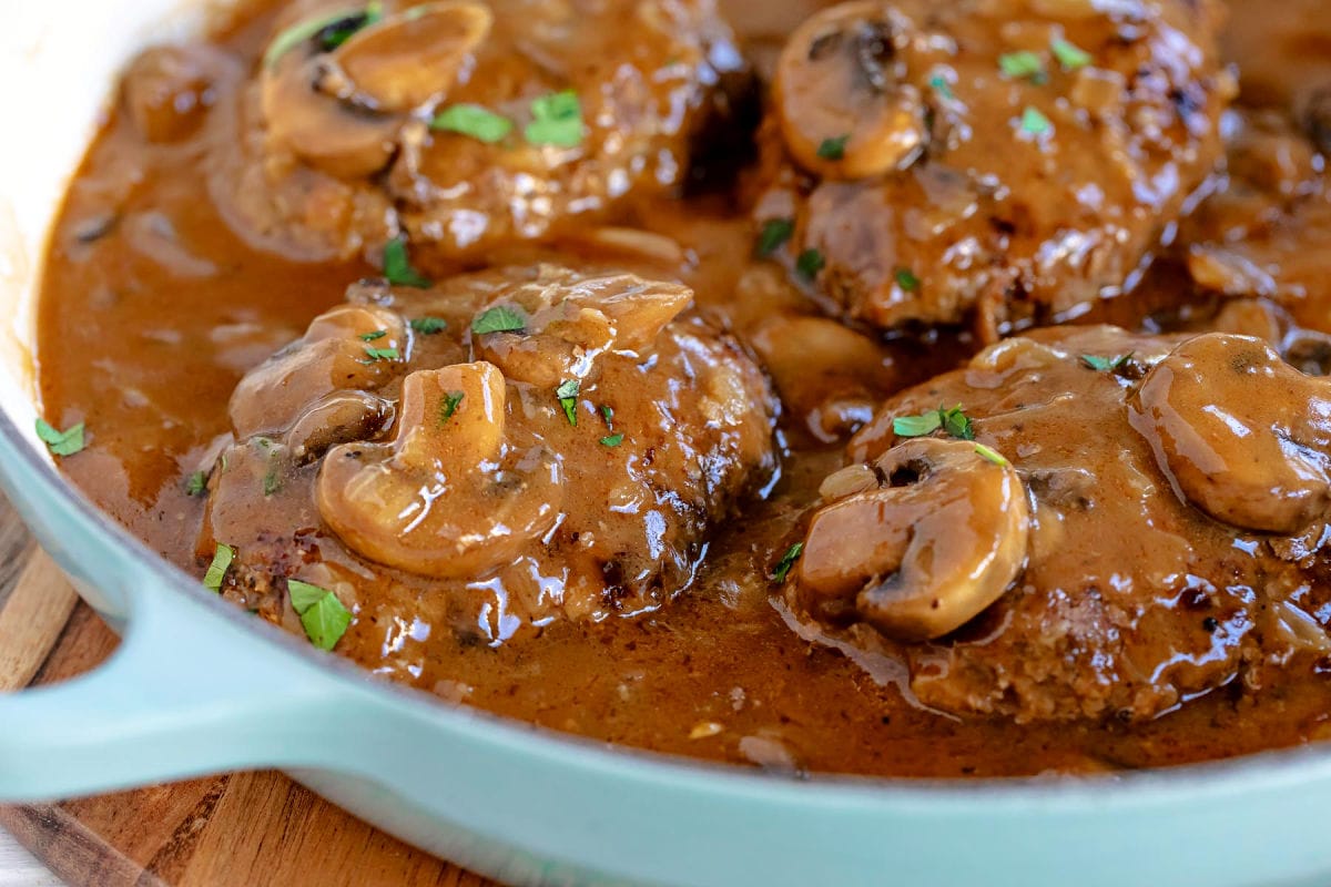 wide shot of salisbury steaks in aqua skillet ready to be served. 