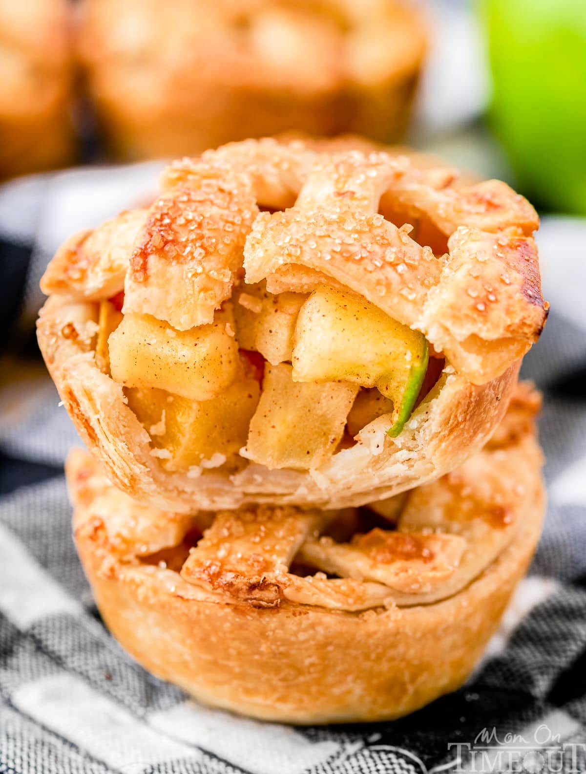 two small apple pies stacked with one having a bite taken from it.