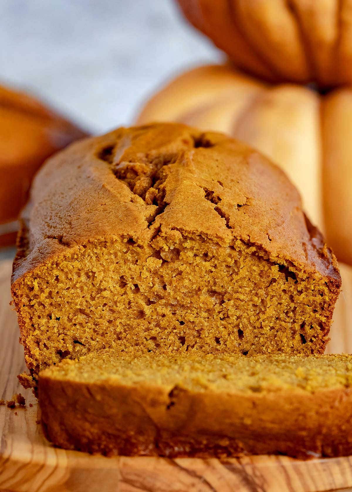 pumpkin bread on wood board with one slice cut off.