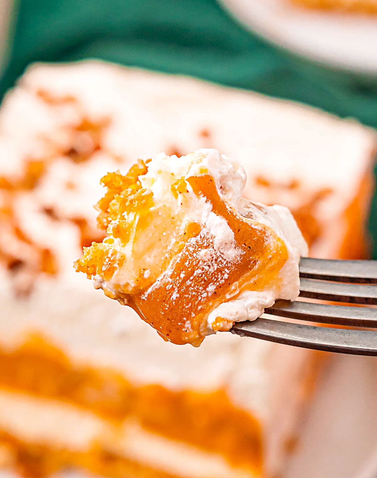 bite on fork of pumpkin delight layered dessert with the rest of the dessert in the background.