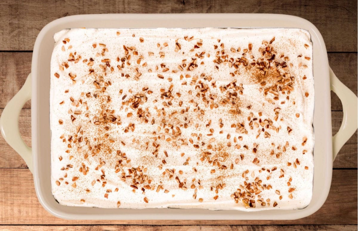 pumpkin delight in a large baking dish topped with cool whip, pecans and pumpkin pie spice.
