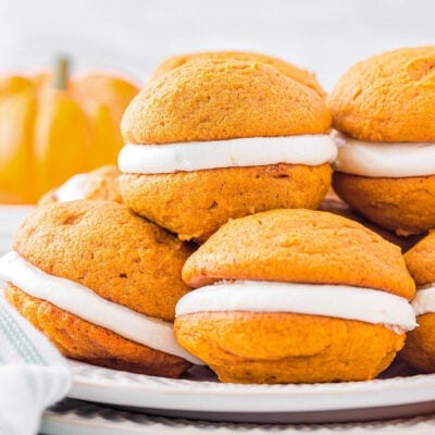 plate with six pumpkin whoopie pies stacked on each other.