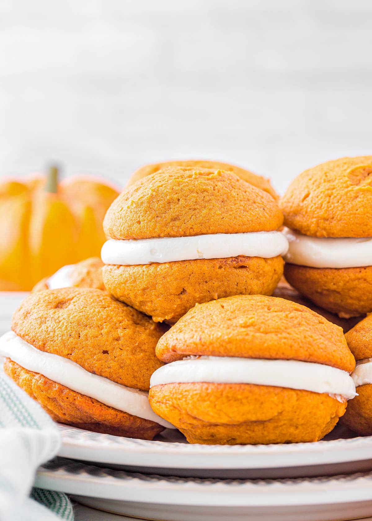 plate with six pumpkin whoopie pies stacked on each other.