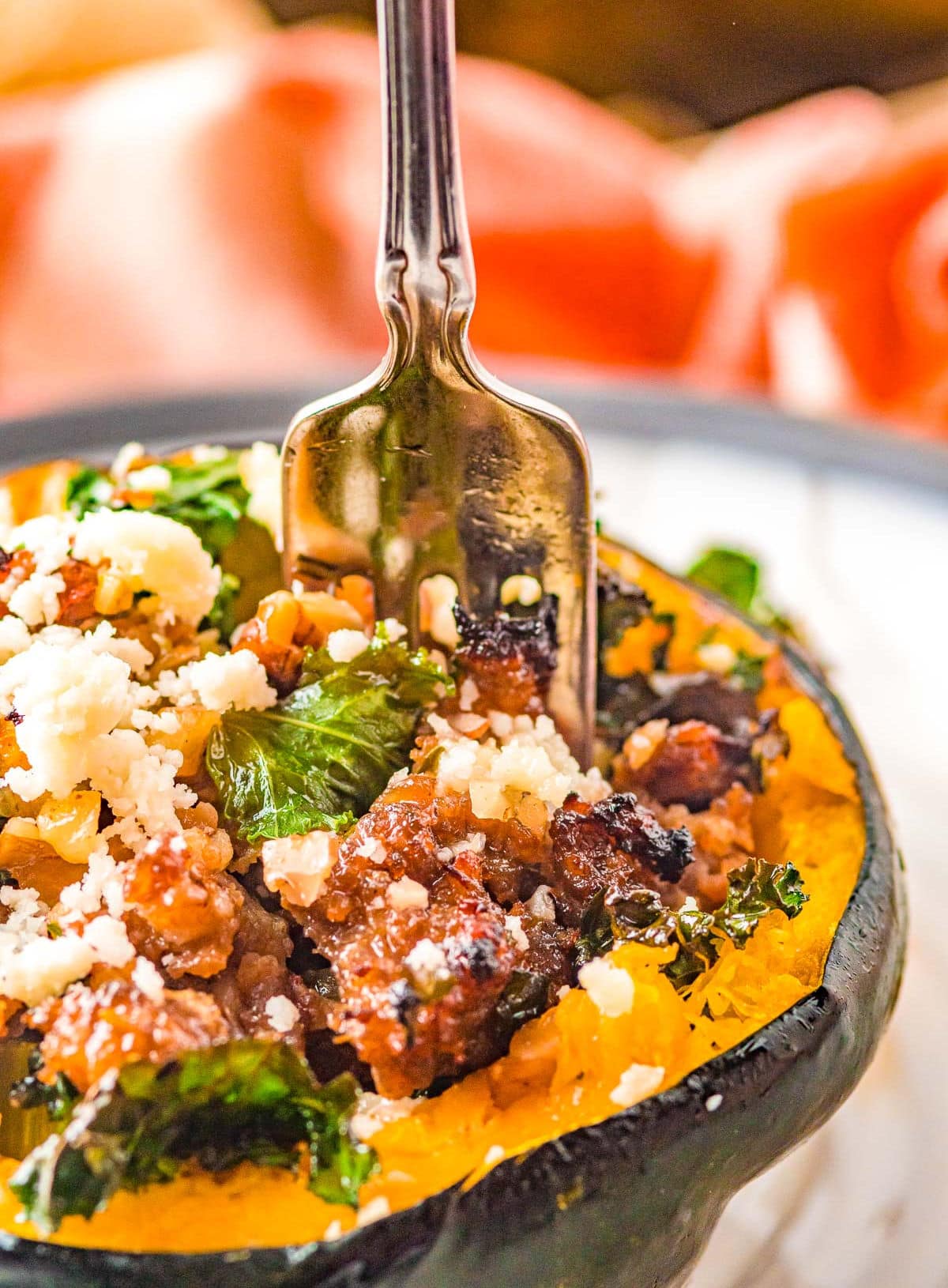 fork going into acorn squash that has been filled with a sausage stuffing mixture.