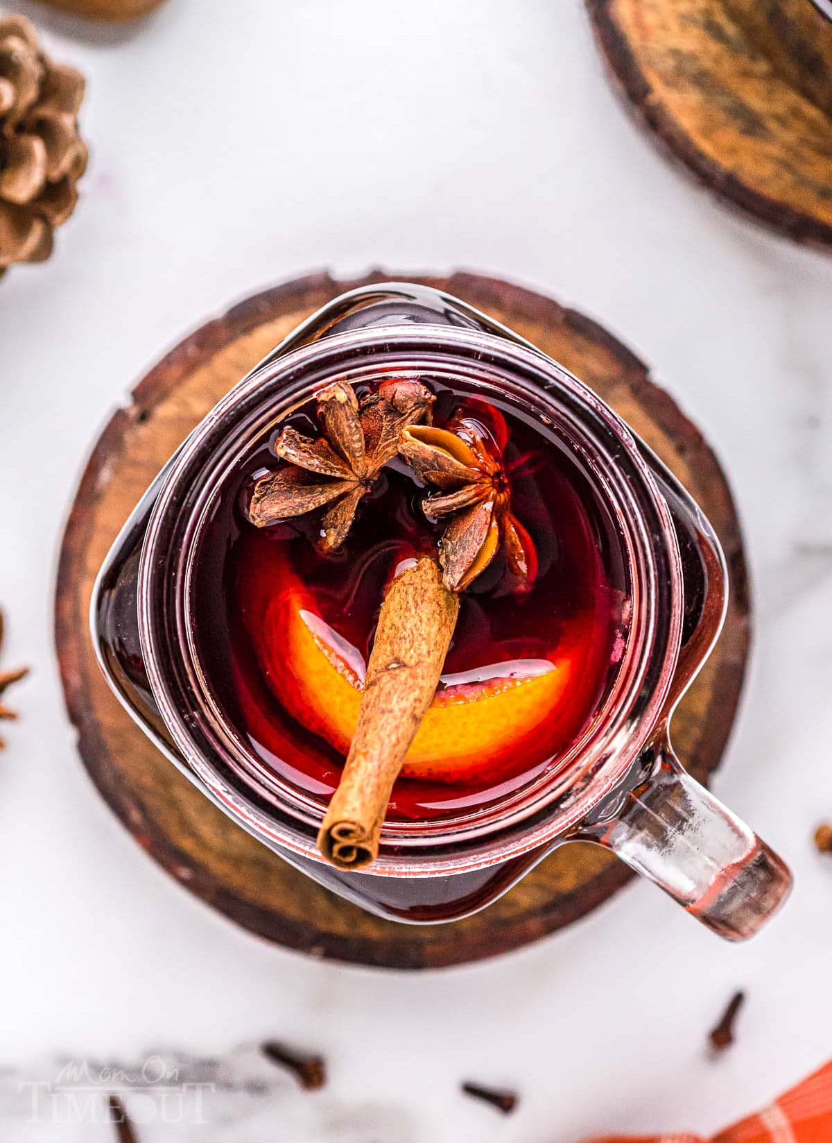 top down look into ball glass jar filled with mulled wine and garnished with a cinnamon stick, orange slice and star anise.