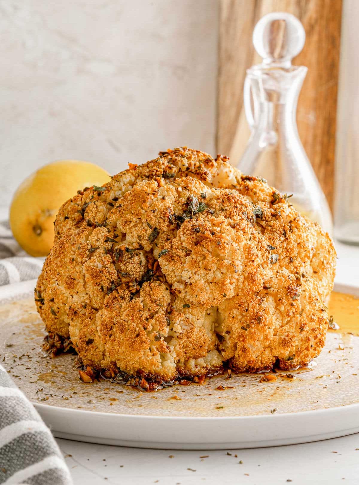 whole roasted cauliflower sitting on white plate ready to be enjoyed.