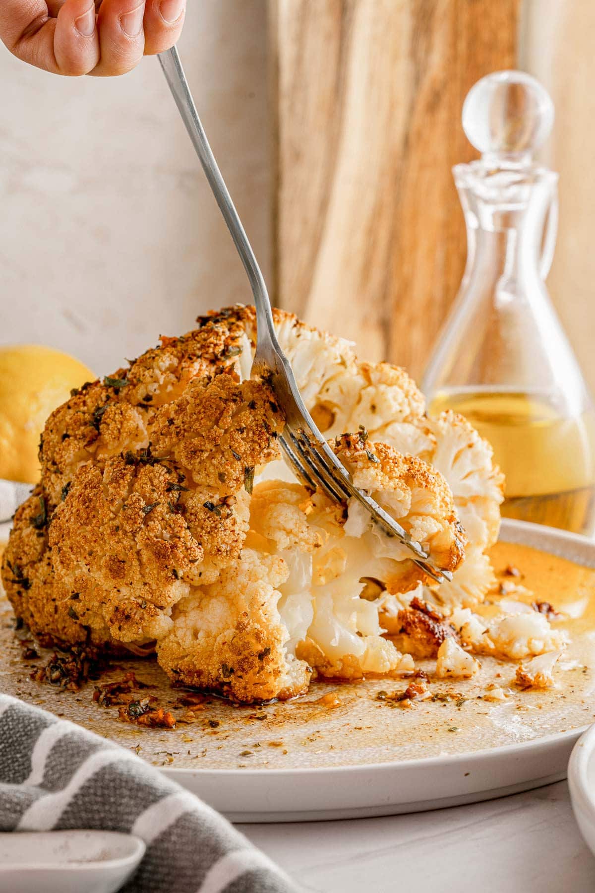 fork pulling off a piece of cauliflower from a whole baked cauliflower.