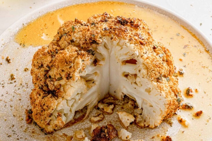 shot looking down at a roasted cauliflower head that has been drizzled with olive oil and seasoned with paprika and parsley.