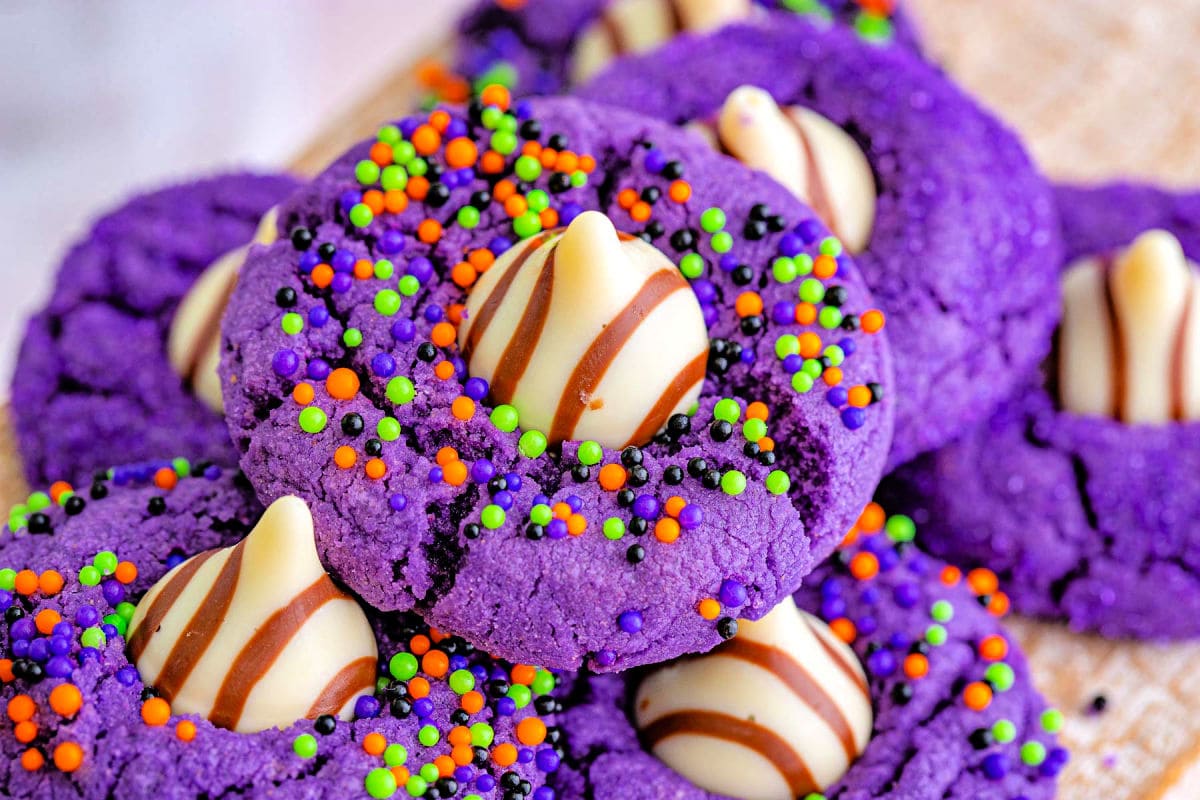 witch hat cookies made in the style of peanut butter blossoms with colorful sprinkles and purple sanding sugar.