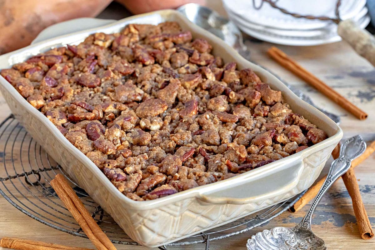 a brown baking dish with a sweet potato casserole in it sitting on a cooling rack.