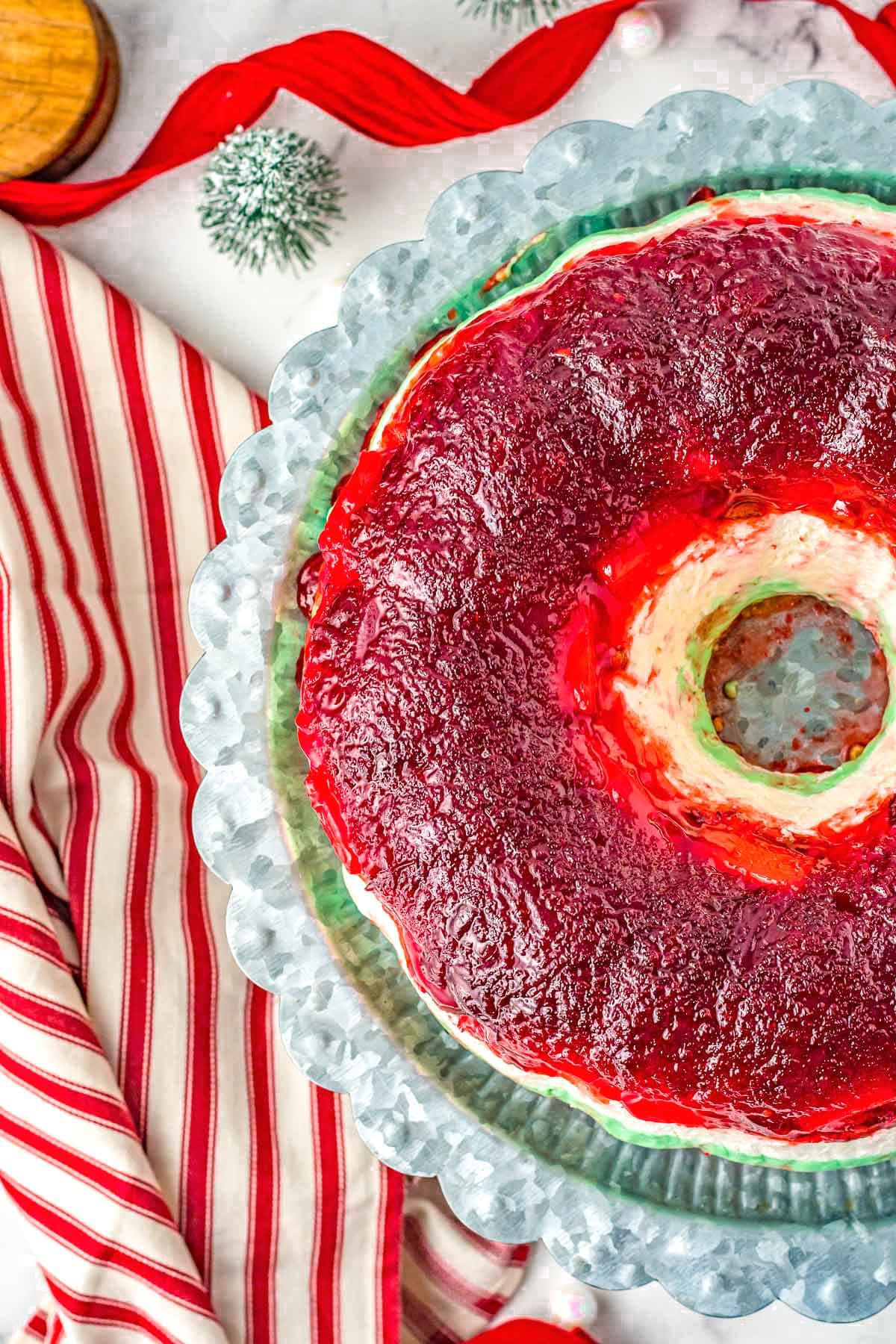 three layers of jello salad made in a bundt pan that has been placed on a galvanized metal cake stand and is ready to serve.