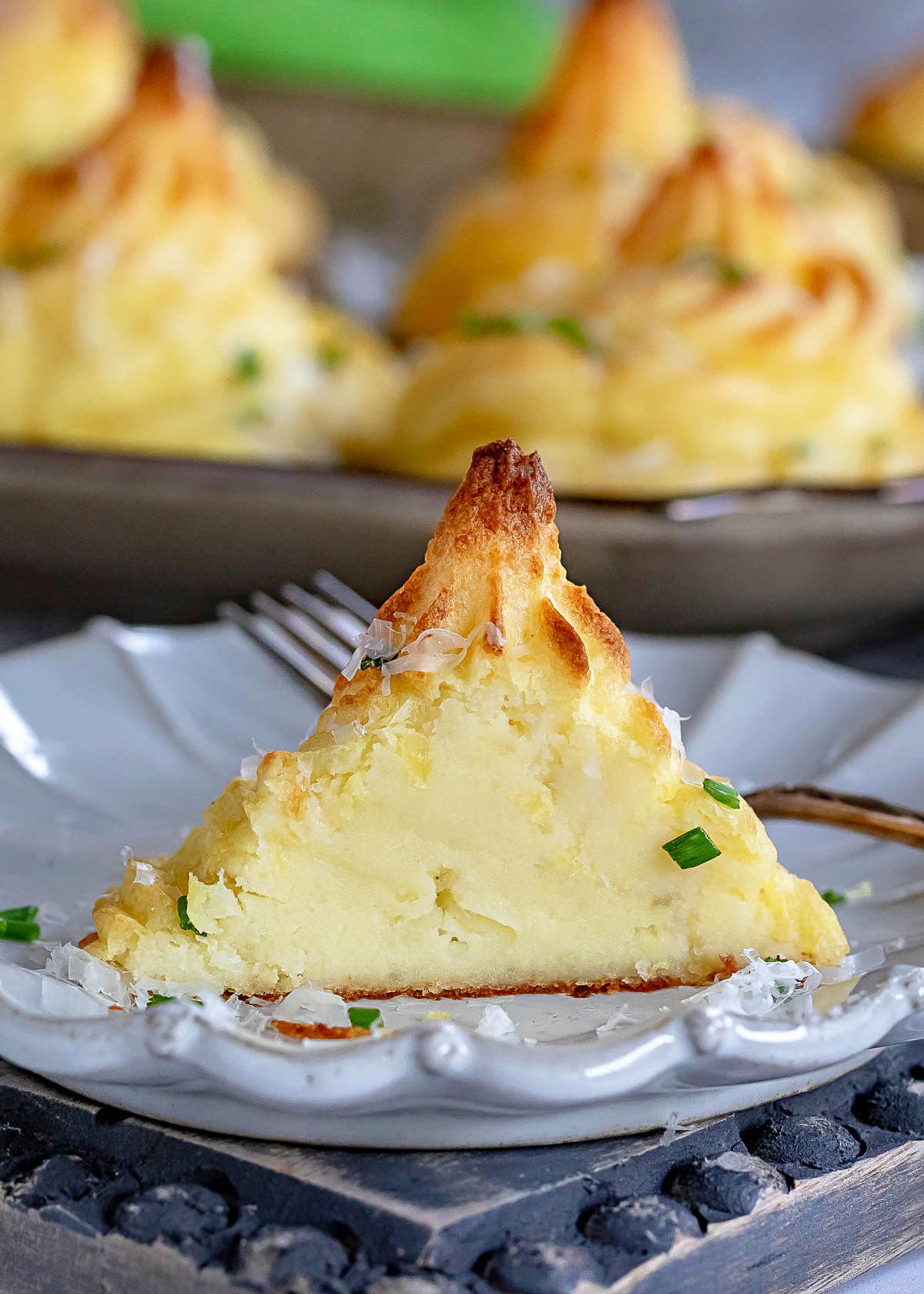 one duchess potatoes serving cut in half and sitting on a small plate revealing the creamy interior.