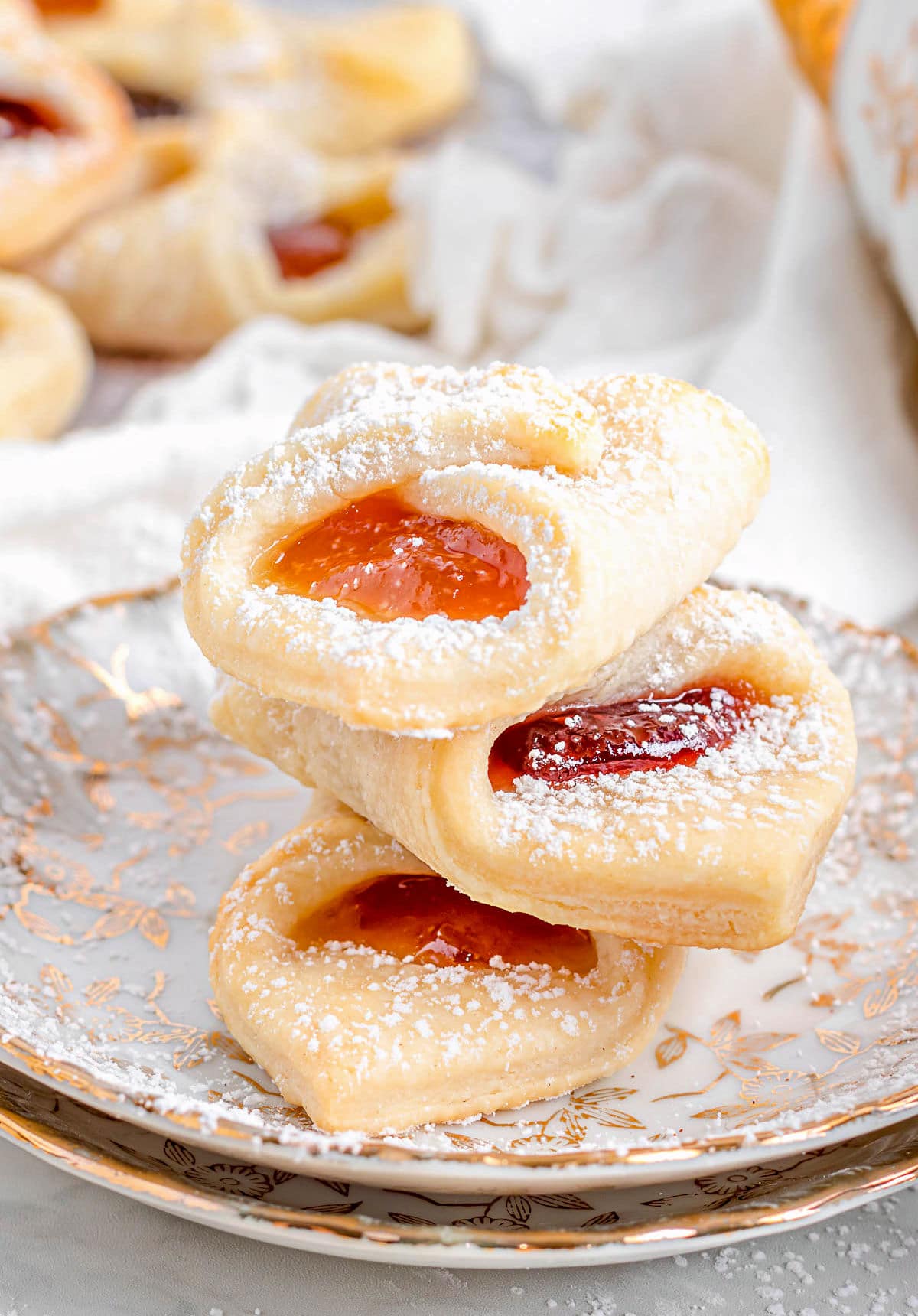 three kolackzi cookies stacked on each other on two gold rimmed plates.