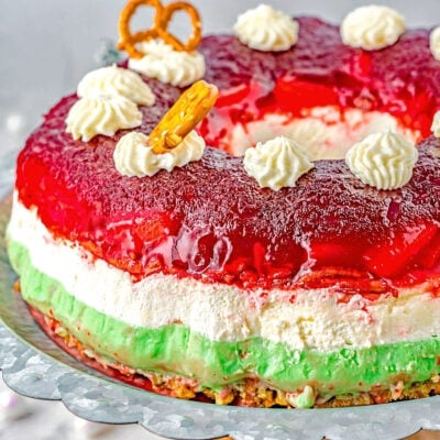 three layered cranberry dessert salad with red white and green layers on a wood pedestal.