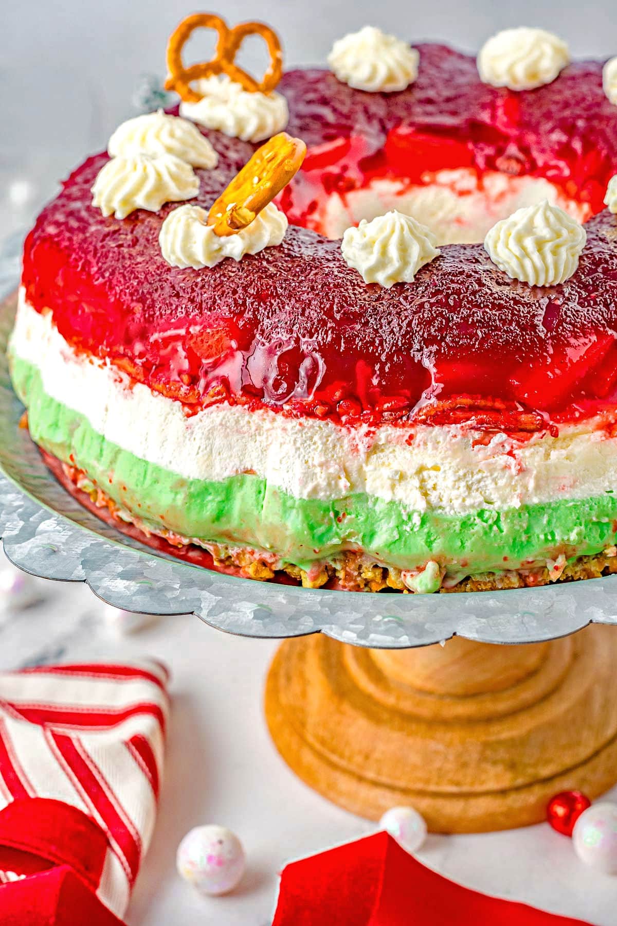 three layered cranberry dessert salad with red white and green layers on a wood pedestal.