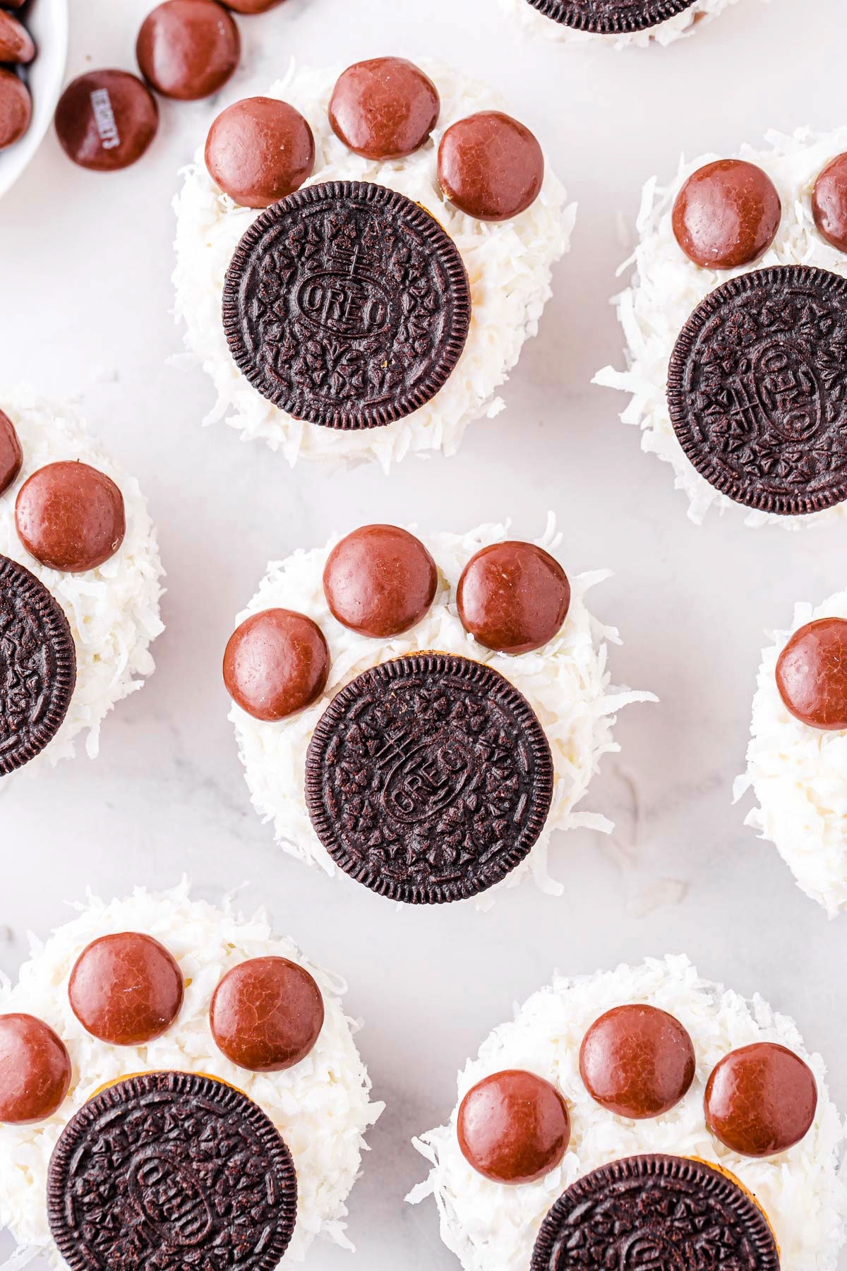 six cupcakes decorated to look like polar bear paws with oreos and coconut.