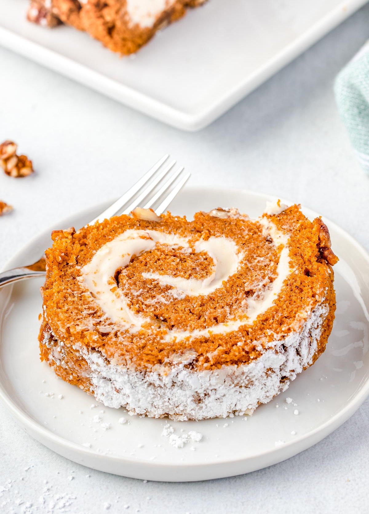 slice of pumpkin roll on a white plate with a small fork.