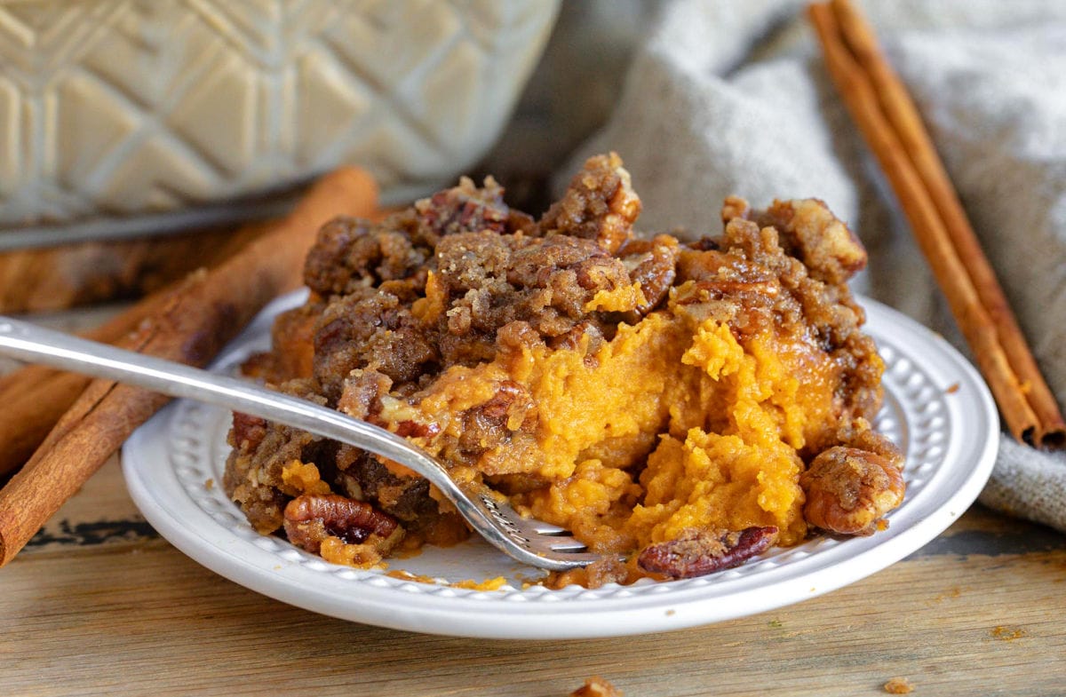 small plate with sweet potato casserole being eaten with a fork.