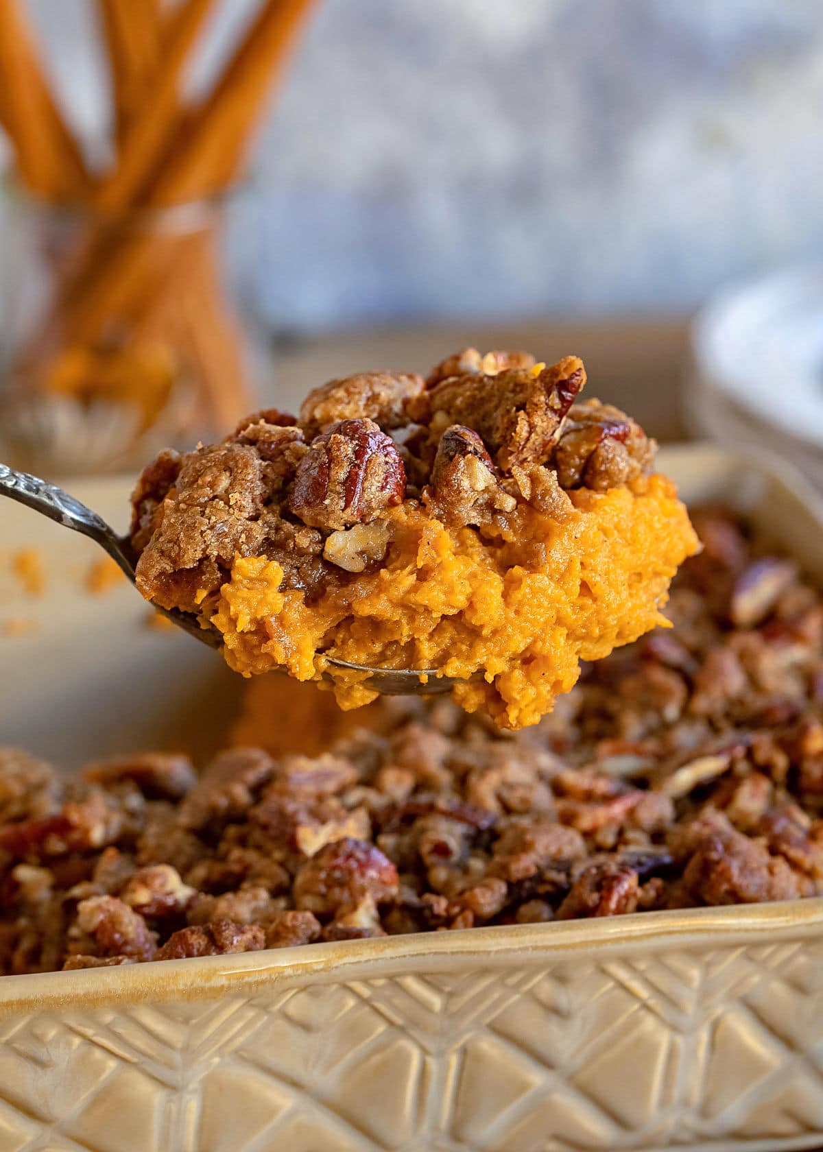 big scoop of sweet potato casserole held above the baking dish.