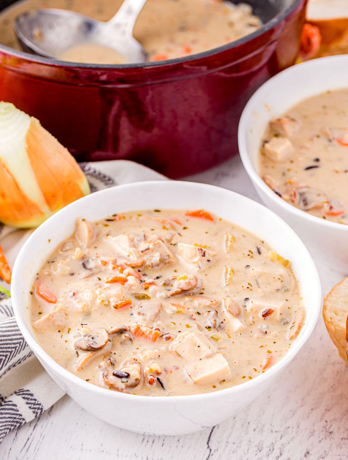 white bowl of soup sitting in front of dutch oven ready to be served.