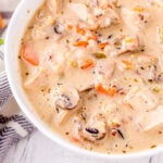 close up look at turkey soup with wild rice and mushrooms in a white soup bowl.