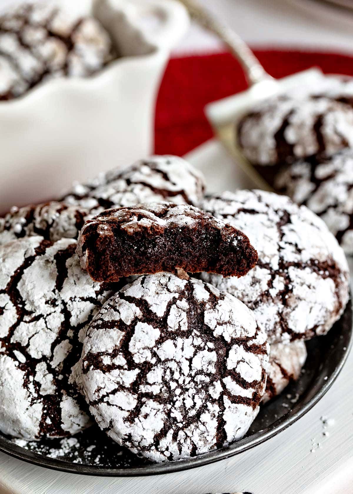 plate of crinkle cookies with the top cookie broken in half showing the fudgy chocolate interior.