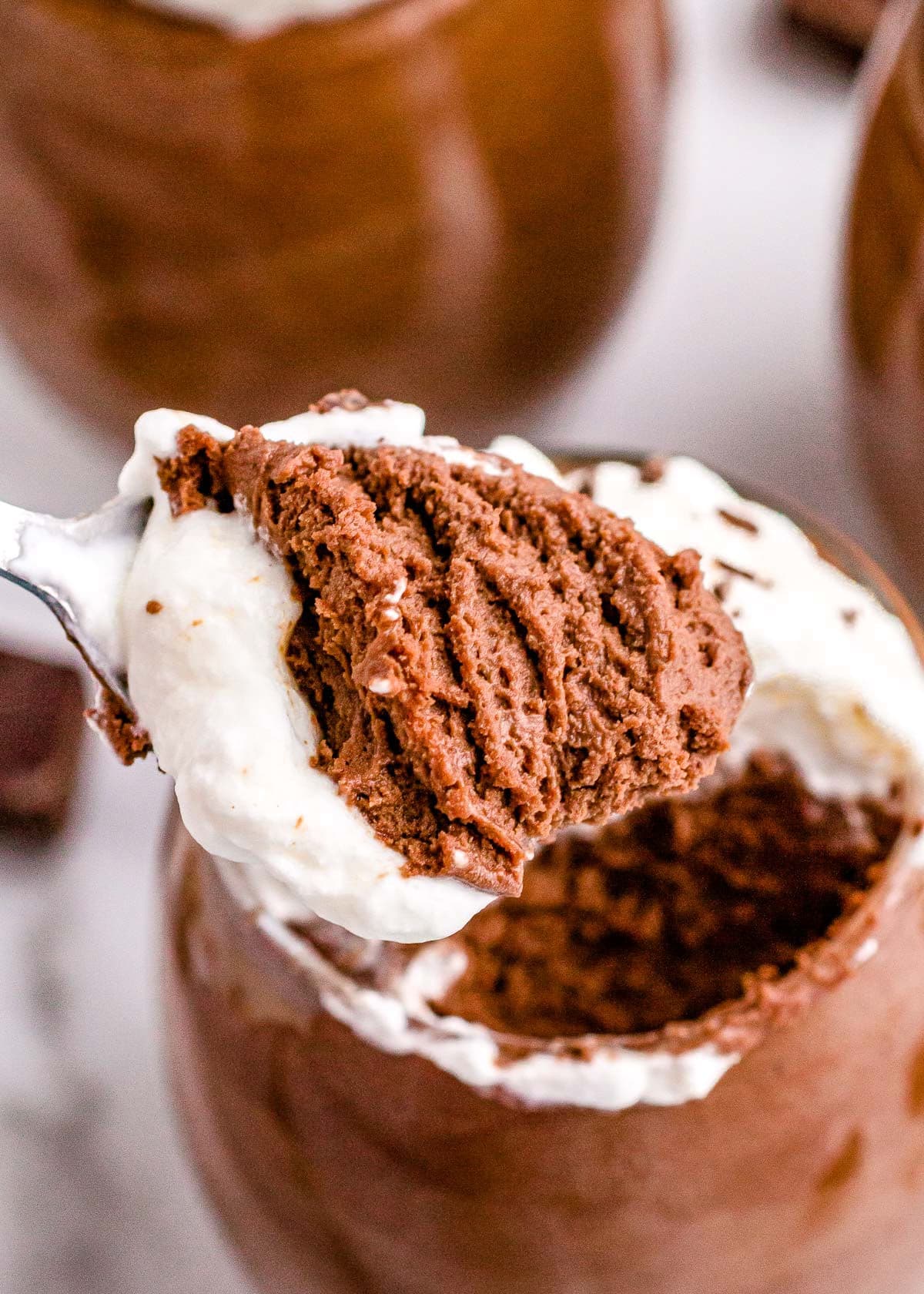 spoonful of chocolate mousse held over the glass it was served in.