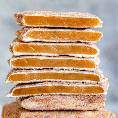 square churro toffee stacked on one another with several pieces broken in half so you see the toffee, the white chocolate layer and cinnamon sugar coating.