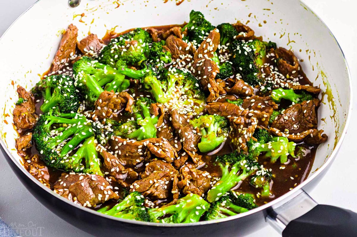 beef and broccoli recipe still in the skillet with white interior. white sesame seeds sprinkled on top. ready to serve.