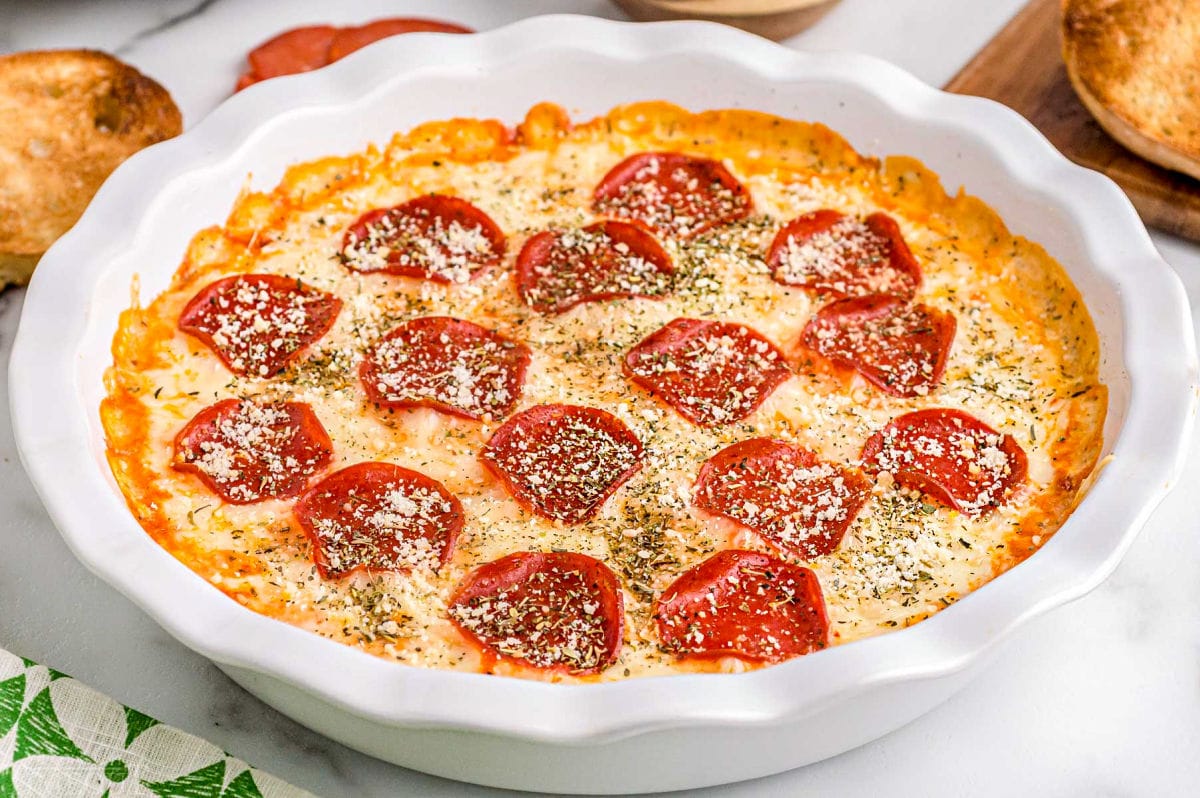 close up look at the baked pepperoni pizza dip topped with Italian seasoning and grated Parmesan cheese.