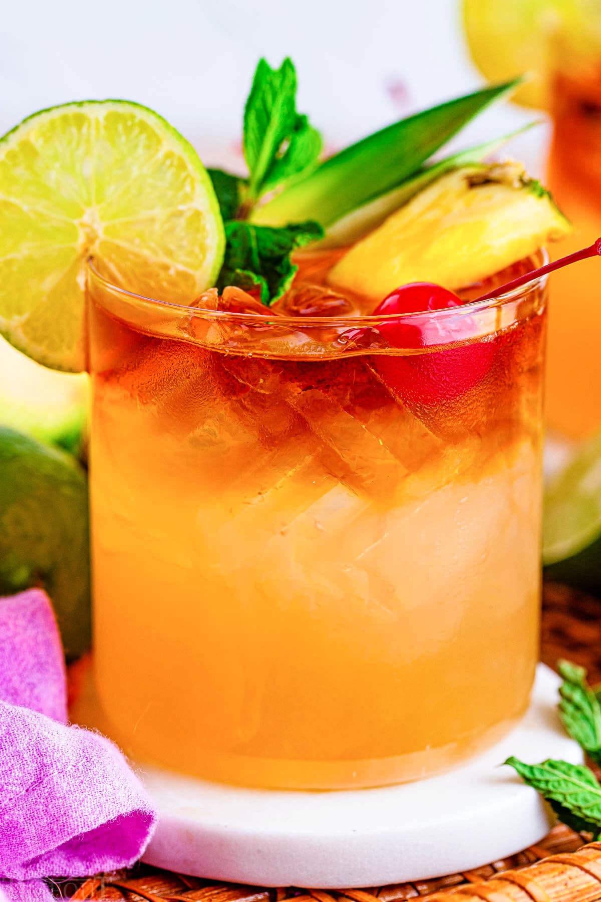 close up look at a mai tai with lots of fruit garnish including cherry, pineapple, lime and mint.