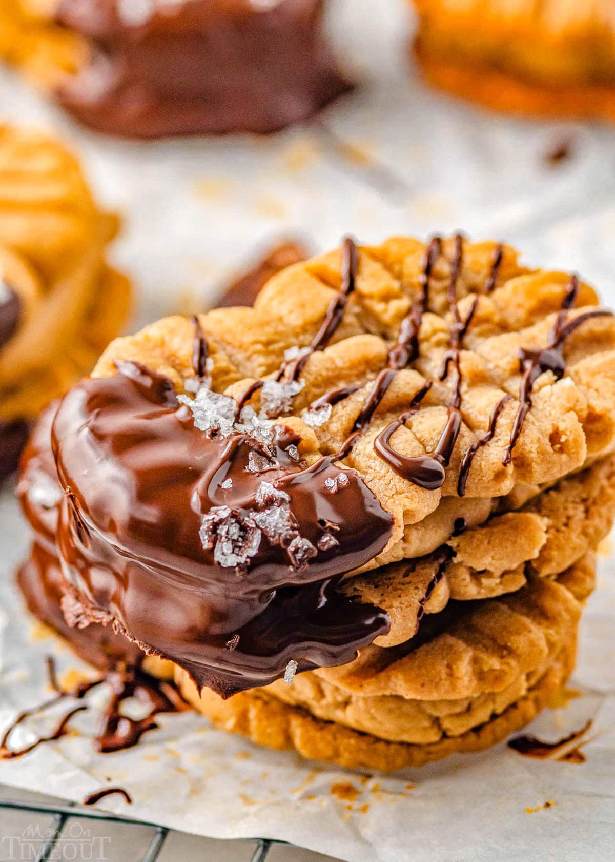 close up look at three nutter butter cookies stacked each dipped in chocolate and sprinkled with flaky sea salt.