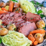 serving plate filled with slices of corned beef, cabbage wedges, carrots and creamer potatoes all ready to be enjoyed.