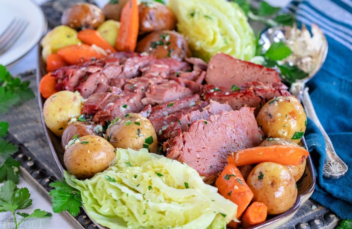 serving plate filled with slices of corned beef, cabbage wedges, carrots and creamer potatoes all ready to be enjoyed.