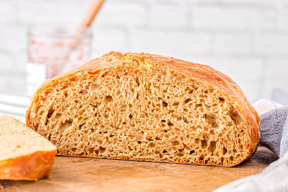 loaf of bread sliced in half sitting on wood board.