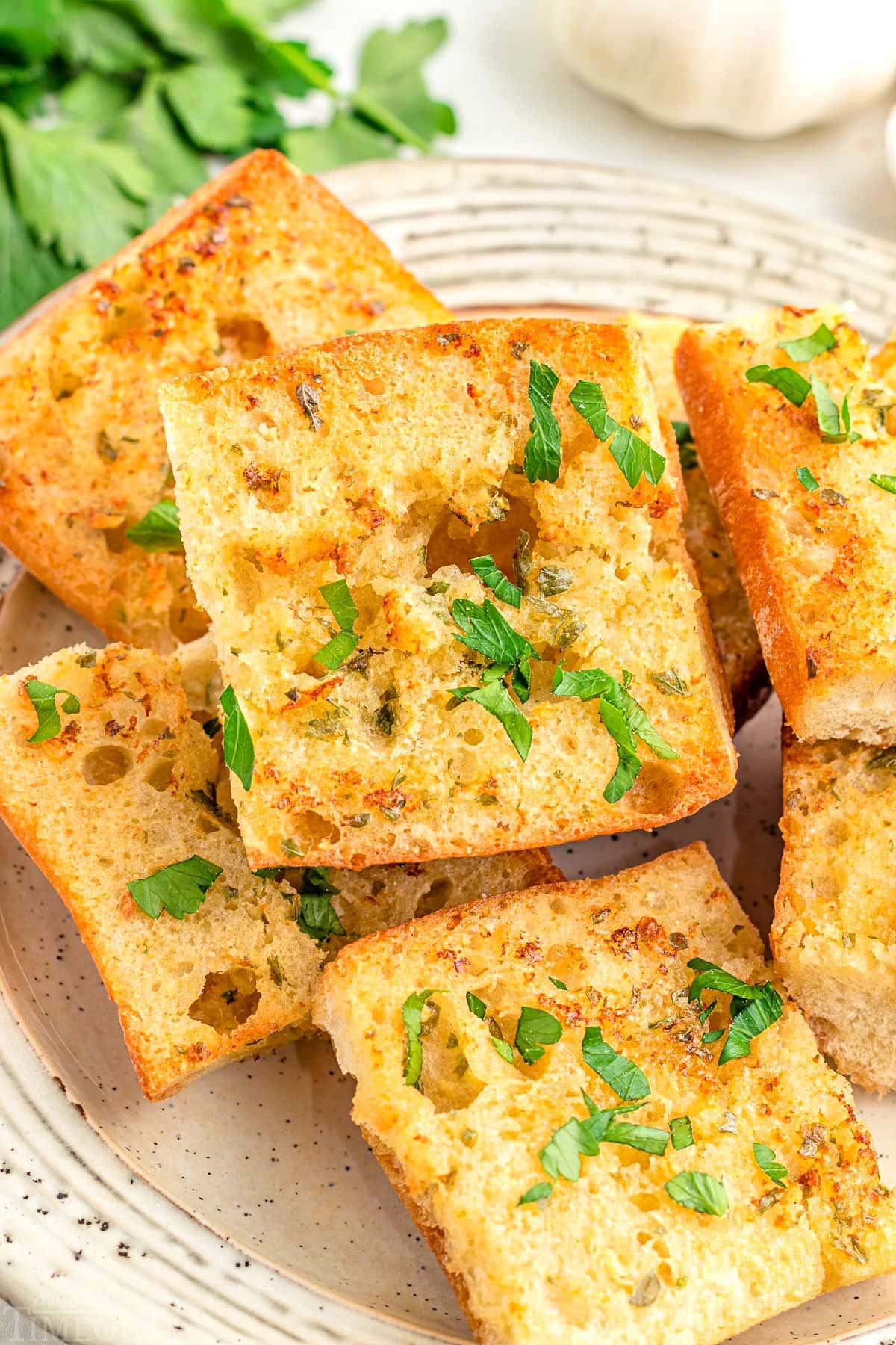 plate topped with 6 or 7 pieces of garlic bread that was made in the air fryer. garnished with fresh chopped parsley.