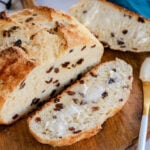 top down look at loaf of irish soda bread with one slice cut off and buttered on a round wood board.