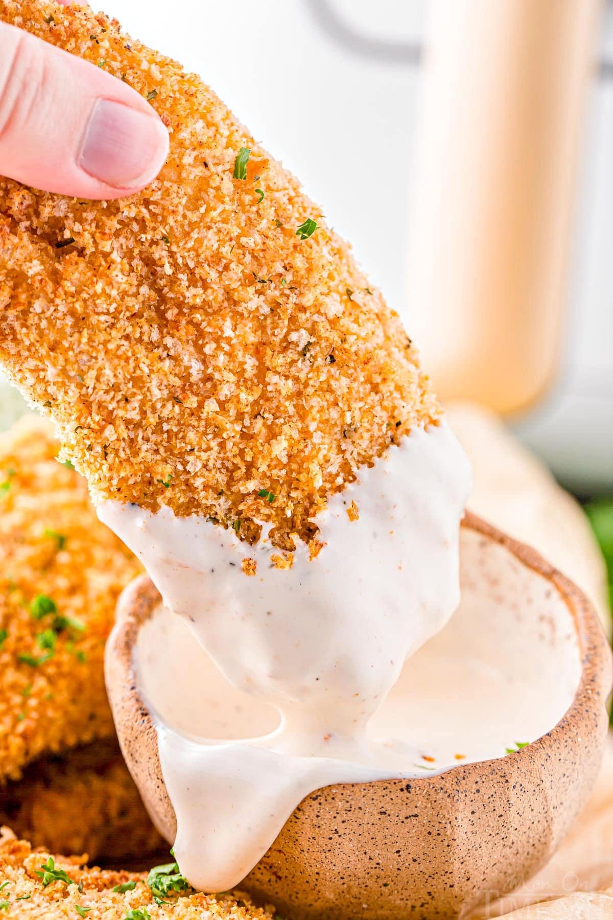 chicken tender being dipped into fry sauce in a small bowl.