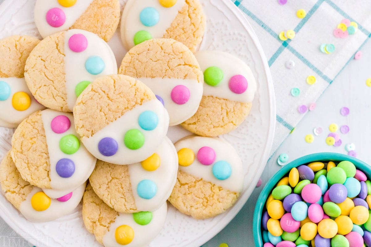 top down look at plate of Easter cake mix cookies decorated with M&Ms sitting on a teal and white napkin and next to a bowl of M&Ms.