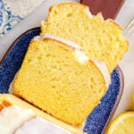 top down look at two slices of limoncello cake on a blue glazed clay cutting board. you can see the rest of the loaf and the glaze on top as well.