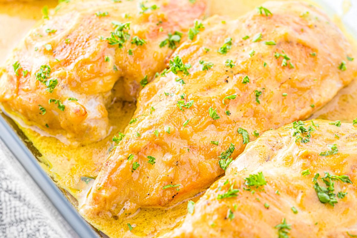 honey mustard chicken breasts baked in a glass baking dish ready to be served all topped with a savory honey mustard sauce.